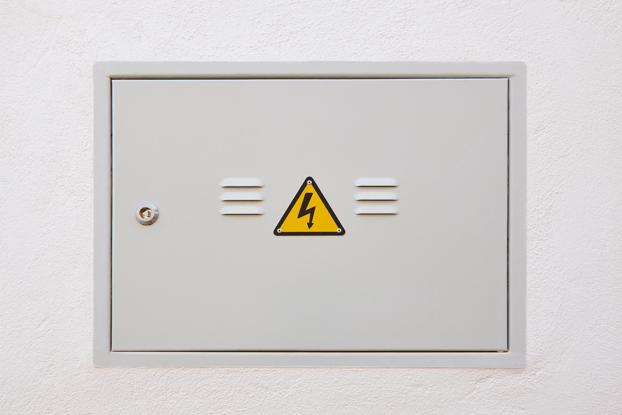 Electric meter box metallic door and white wall. Warning