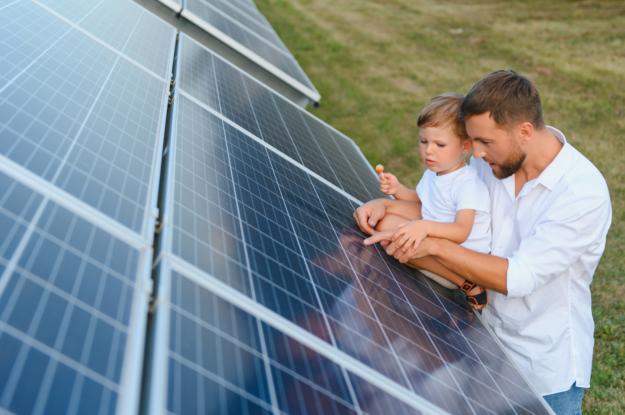 Happy father and his little son are walking near the solar panels. The concept of green energy.