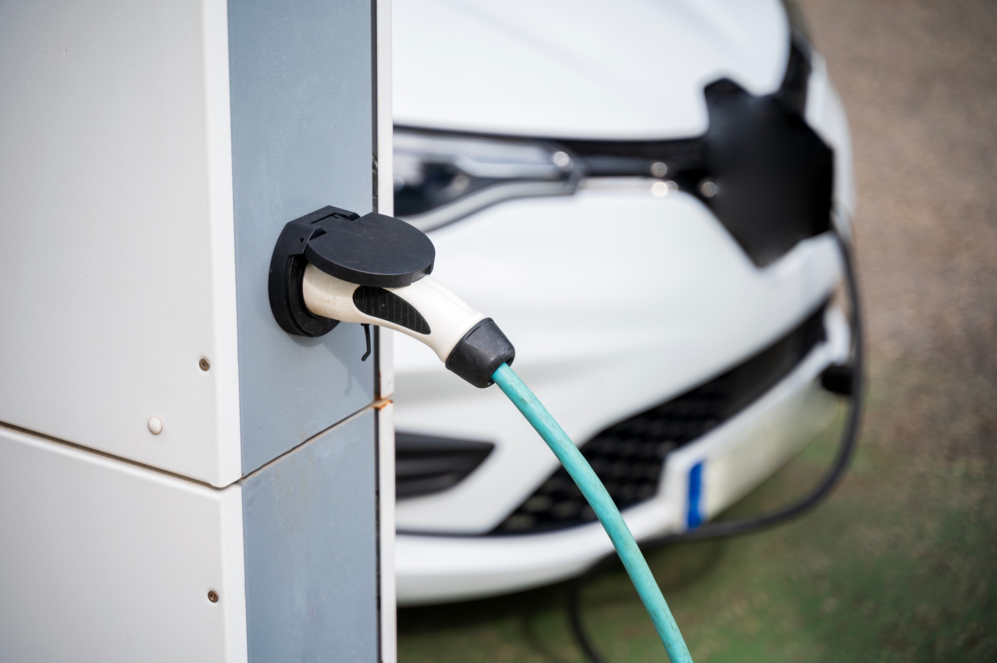 An electric vehicle at a charging station in the city. White e-car that is on the charging cable.